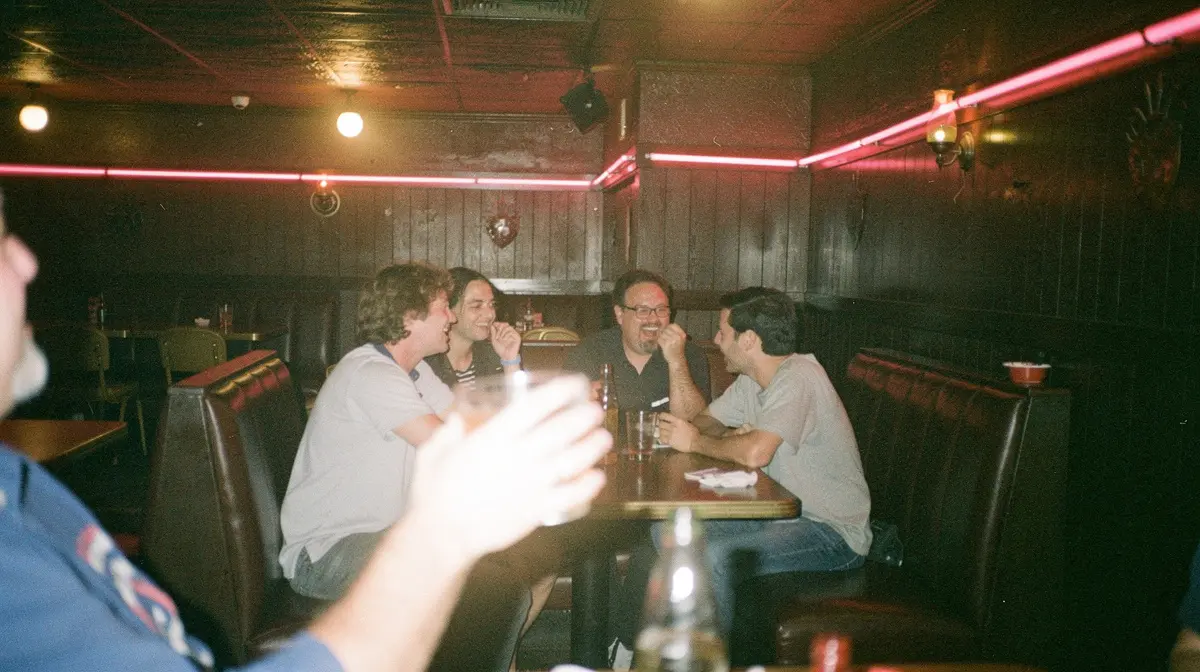 En grupp vänner skrattar i ett bås på en halvmörk bar i Los Angeles på 90-talet, ur filmen Swingers - blackjack på krogen ...